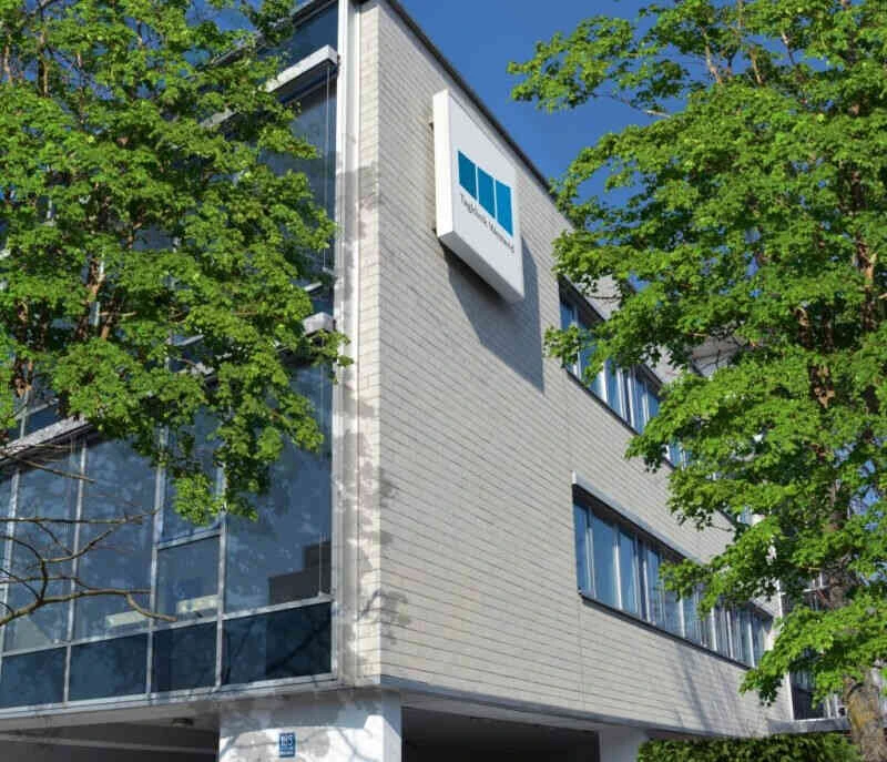 Au&szlig;enansicht des Geb&auml;udes der Psychosomatischen Tagesklinik M&uuml;nchen-Westend der Oberberg Kliniken, mit Kliniklogo an der Fassade und B&auml;umen im Vordergrund
