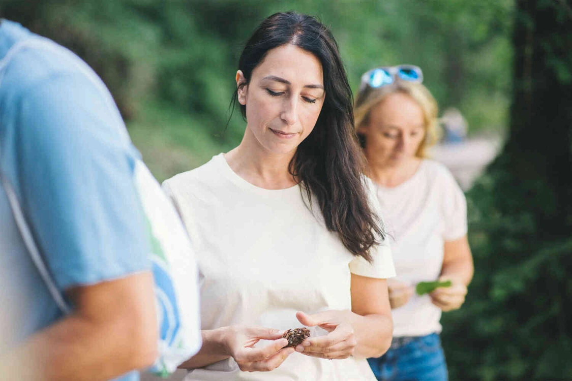 Frau steht drau&szlig;en in einer gruppe und h&auml;lt in ihrer hand eine kastanie