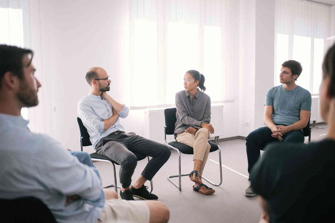 gruppe sitzt in einem wei&szlig;en raum und redet