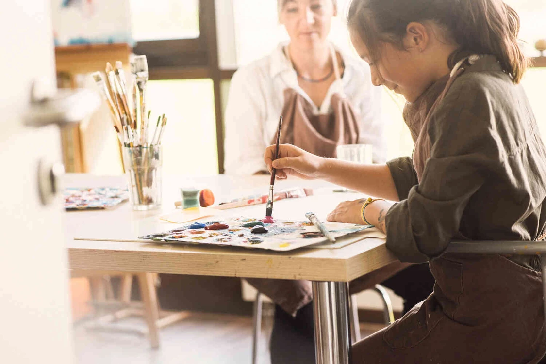 Ein M&auml;dchen malt ein bild w&auml;hrend eine frau zu guckt